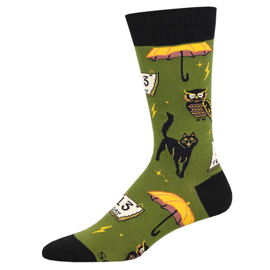 A pair of green crew socks with a pattern of black cats, umbrellas, and other items associated with superstition.