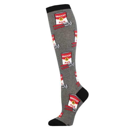 A pair of knee-high socks with a pattern of soup cans and the text 'WHOOP ASS' on them, primarily in gray color with red and white accents.