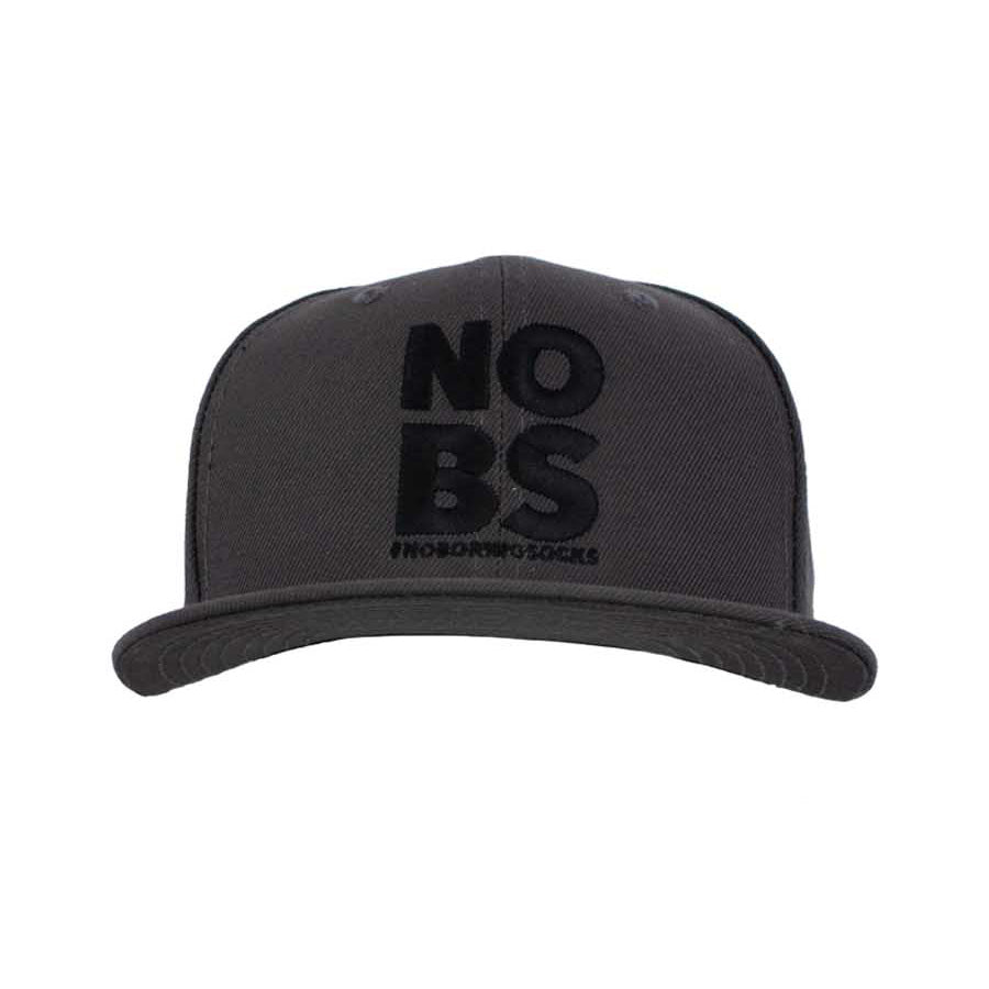 A dark grey flat bill hat with 'NO BS' #NoBoringSocks printed prominently in the center.